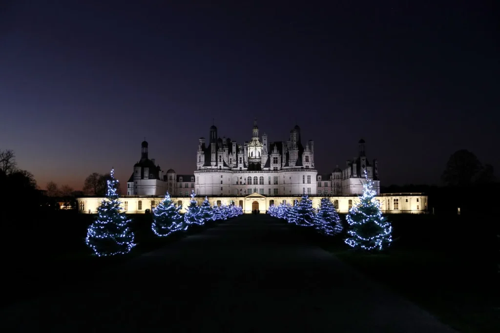 Chateau de Chambord la nuit, illuminé, avec des sapins décorés