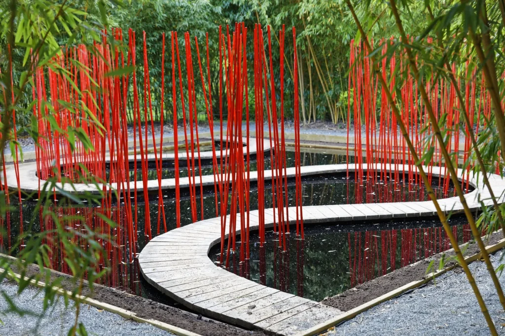Bassin avec des batons de couleur rouge plantés debout qui suivent un chemin qui serpente sur l'eau