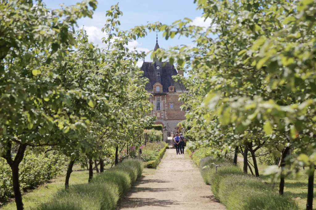 Visiteurs dans une allée du jardin, se dirigeant vers le chateau