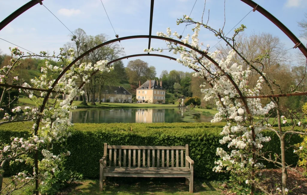 Banc sous une tonnelle de fleurs blanches au bord de l'étang devant la maison