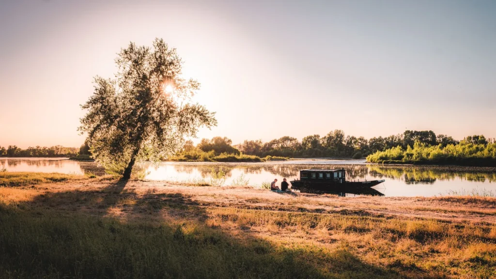 Couple assis sur les bords de Loire, un bateau amarré devant eux