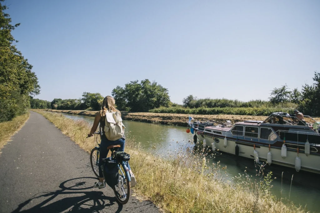 Cycliste sur le bord du canal, un bateau sur le canal est à côté