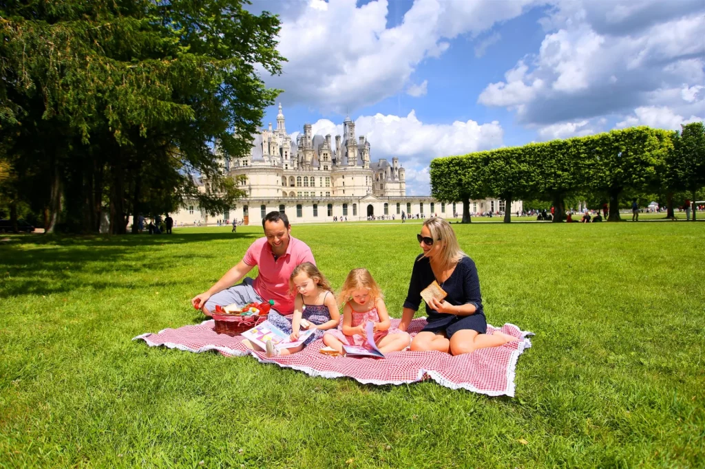 Famille qui pique-nique sur l'herbe devant le château de Chambord