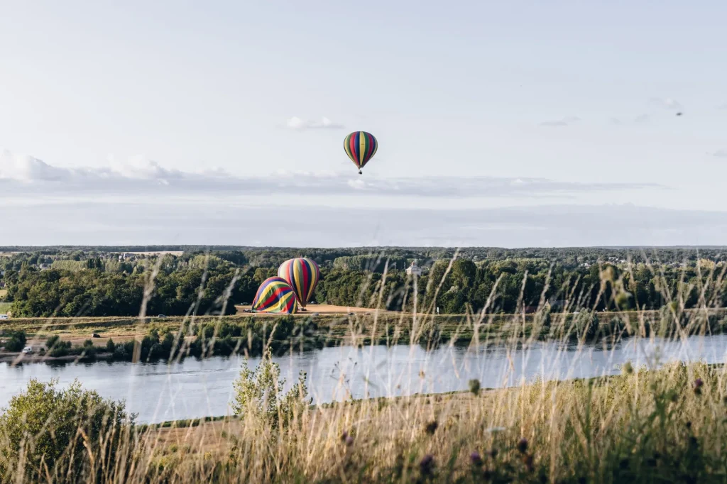3 montgolfières, dont une dans le ciel, au bord de la Loire