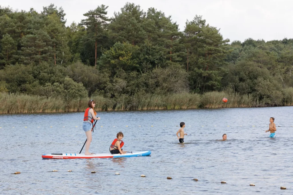 Enfants jouant au ballon dans l'eau et sur un paddle à l'étang de la Vallée à Combreux
