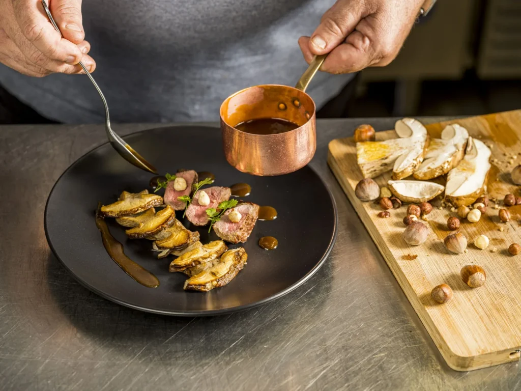 Dans les cuisines de L'Auberge du cheval blanc, Maitre Restaurateur, préparation d'une assiette avec des champignons et une sauce