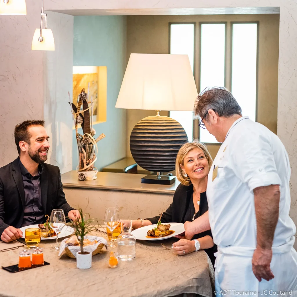 Couple à table au restaurant avec le chef de L'Auberge de l'ile qui dépose une assiette