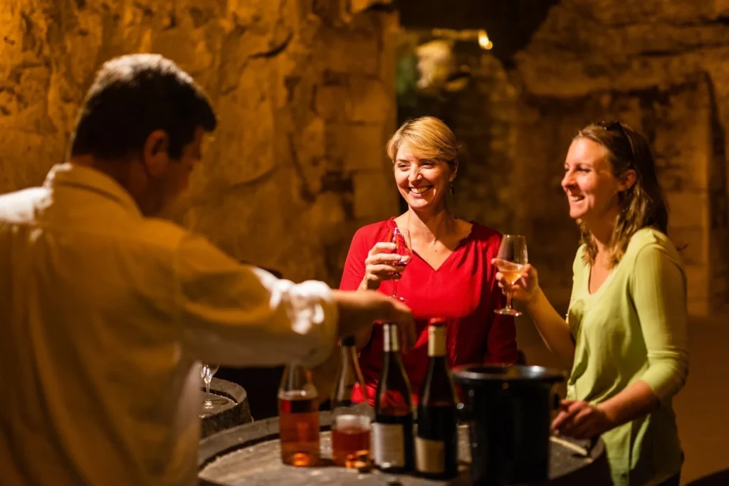 Vignerons faisant déguster ses vins à deux femmes dans une cave