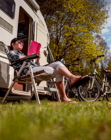 Personne assise en train de lire devant son camping car