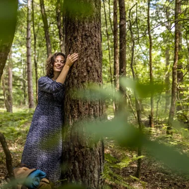 Femme qui fait un calin à un arbre dans la forêt