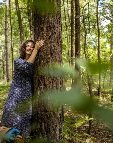 Femme qui fait un calin à un arbre dans la forêt