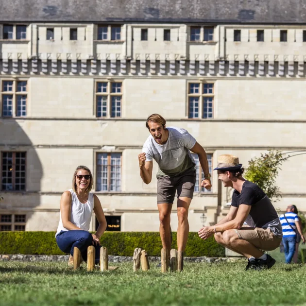 Groupe de personnes jouant aux quilles en bois devant le chateau