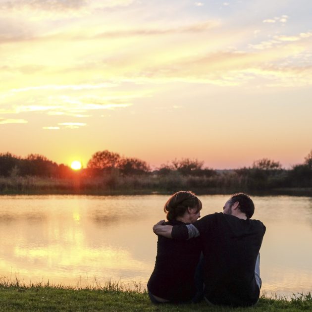Couple assis au bord d'un étang au Grand Fourneau (chambre d'hôtes en Sologne), au coucher du soleil