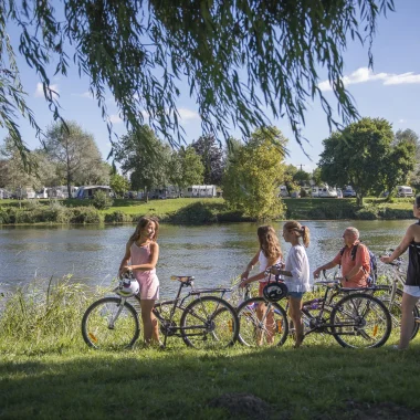 Cyclistes devant un plan d'eau, camping au fond