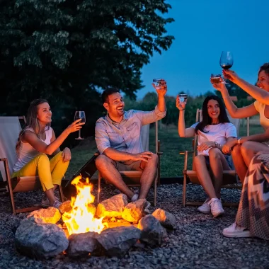 Groupe de personnes autour d'un feu de camp qui boivent un verre